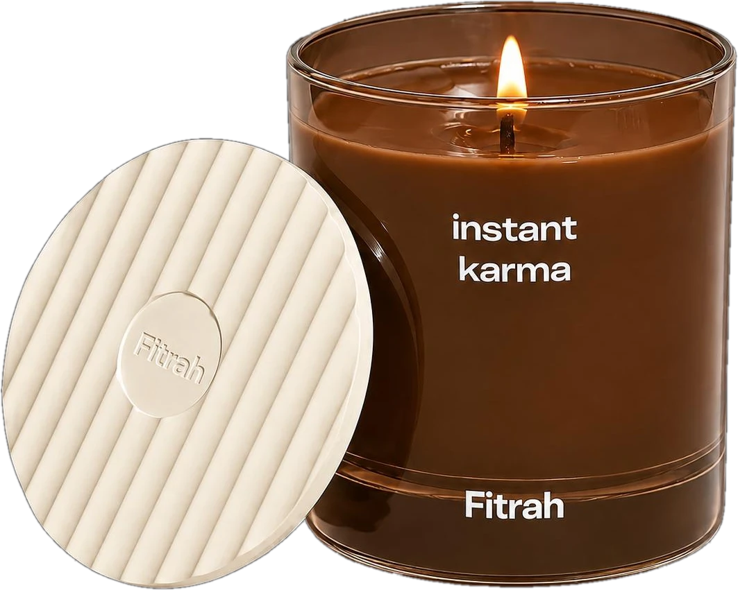 Fitrah Instant Karma candle in amber glass, lit, beside its ribbed ceramic lid